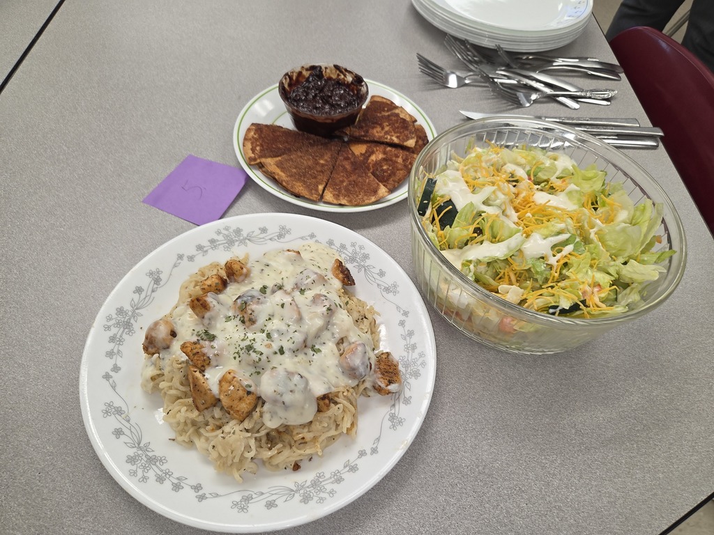 A plate with a chicken pasta dish, a bowl of salad, and plate with fried tortilla's with cinnamon and chocolate sauce on the side.
