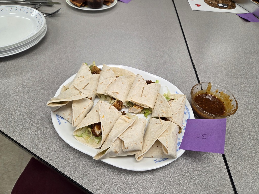 A plate of chicken wraps with hot sauce.