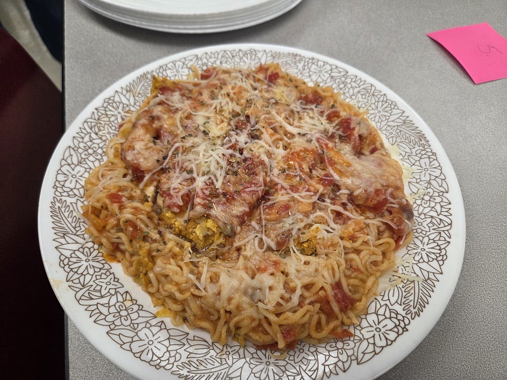 A plate of chicken parmesan on a bed of noodles.