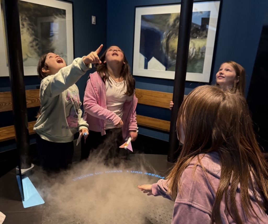4 girls looking up at the tornado exhibit.