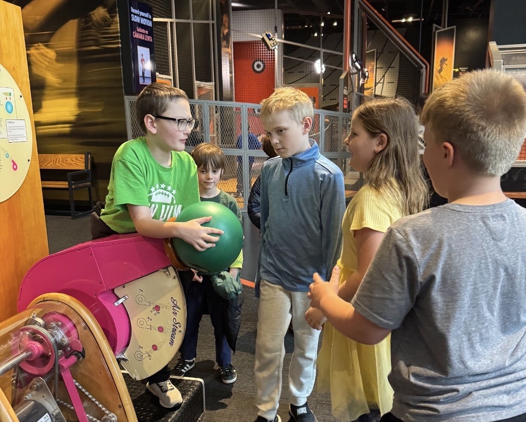 Students gathered around the ball launcher exhibit.