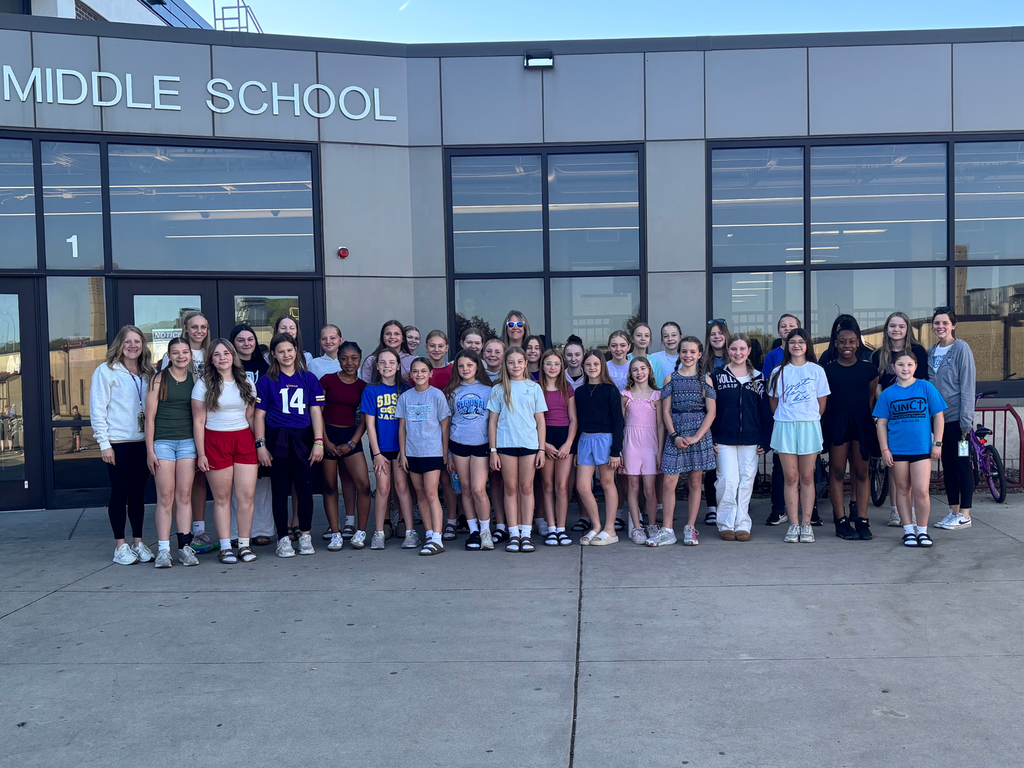 Students and staff of the Walking Club pose in front of the Middle School for a picture.