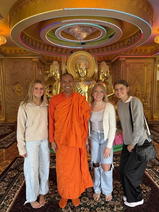 3 students and the Buddhist member, pose for a photo inside the temple.