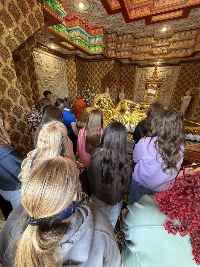 Group of students listening to their guide, looking at a different part of the inside of the temple.