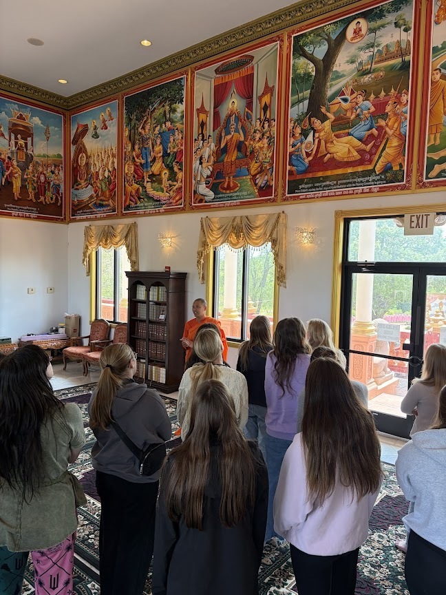 Group of students listening to their guide, pointing to paintings in the temple. Closer look at the paintings.