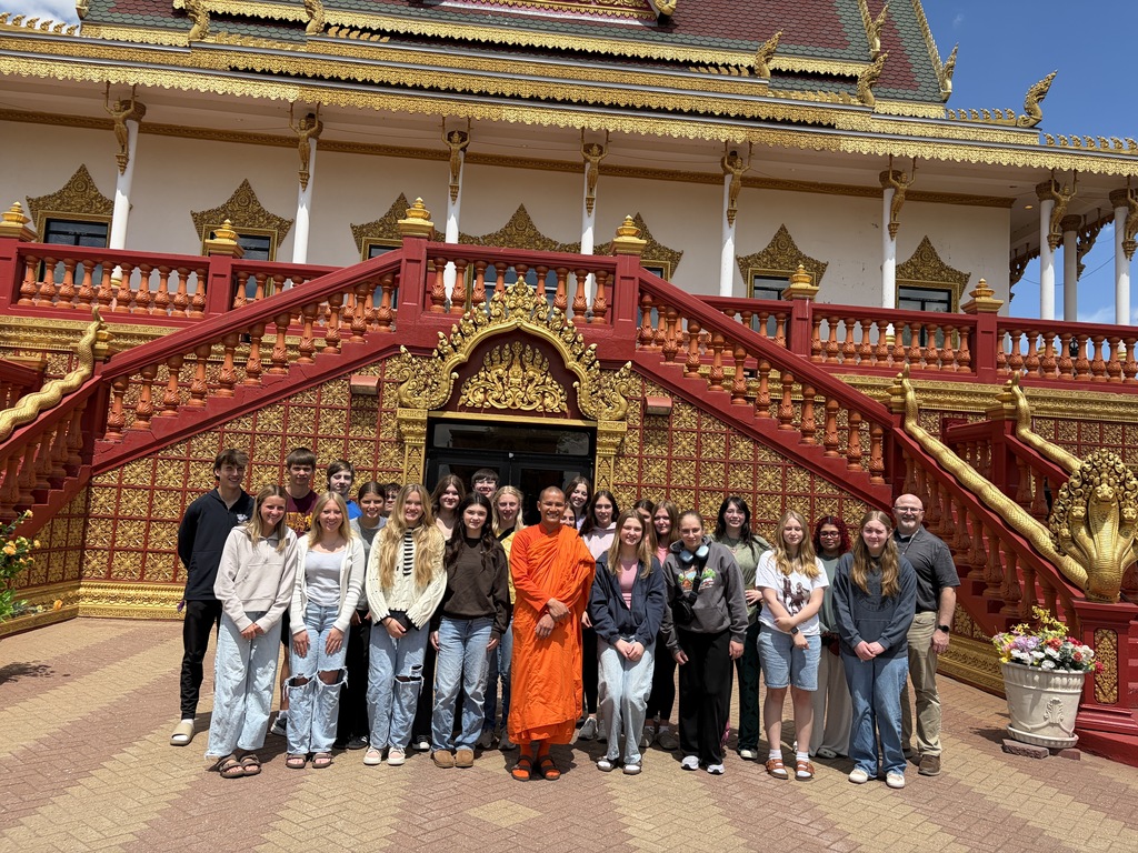 Class and their teacher, along with the Buddhist member, posing for a photo outside the temple.