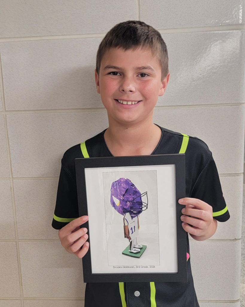 3rd grader Brooks D. Holding a picture of his cardboard sculpture of a Vikings football player.
