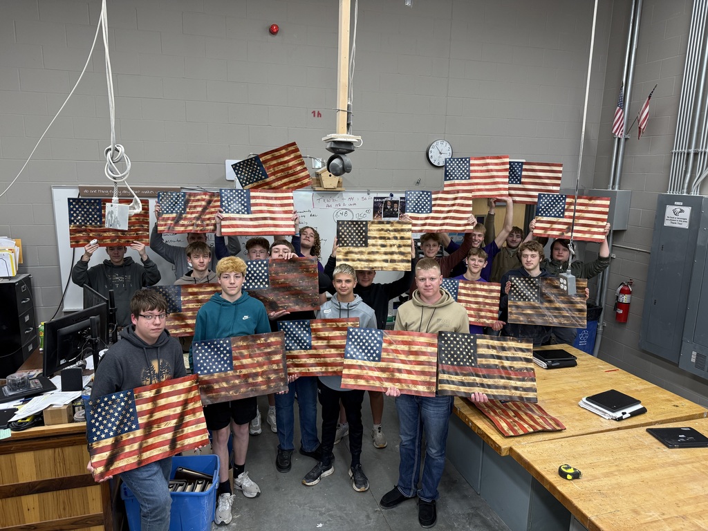 The students in the class each holding up the wooden flag they made.