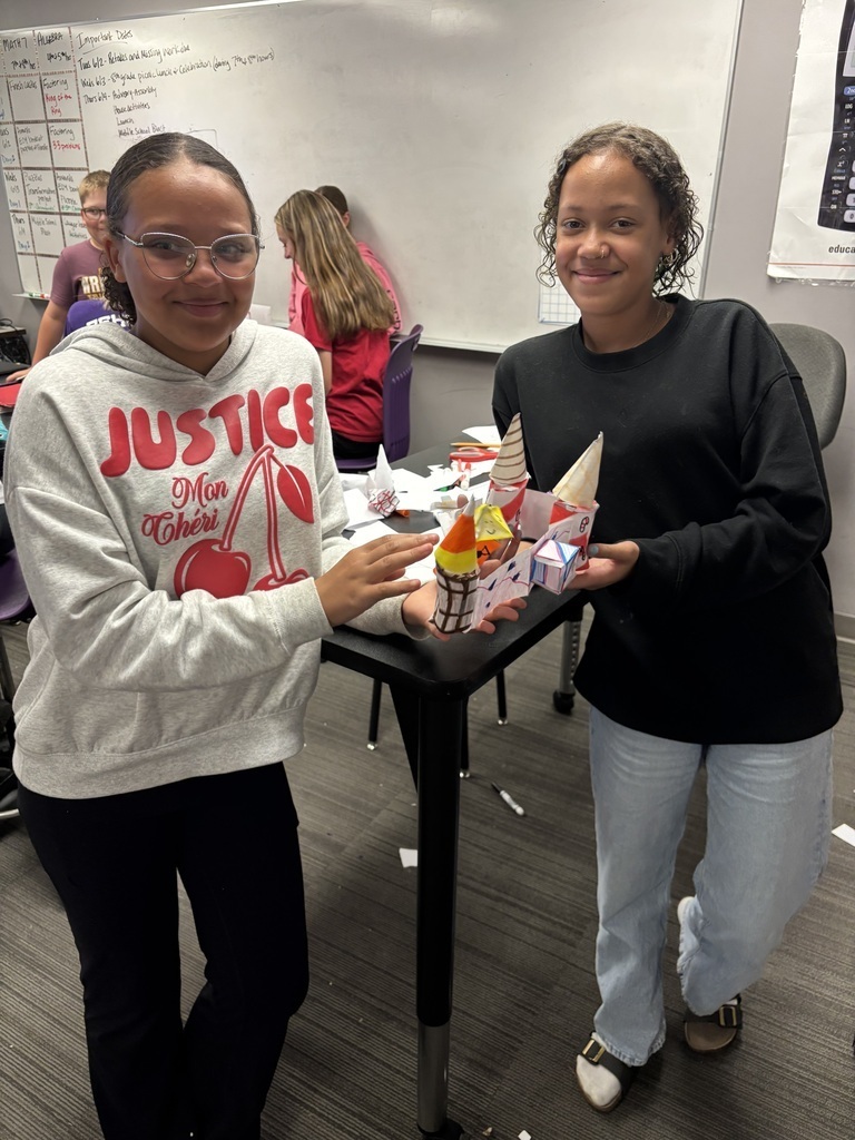 2 students holding their red, white, and yellow castle.