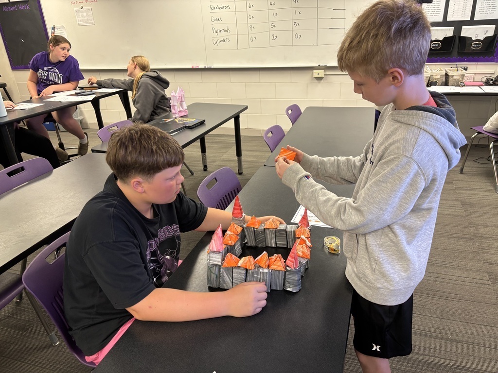 2 students working on their almost finished black and orange castle.