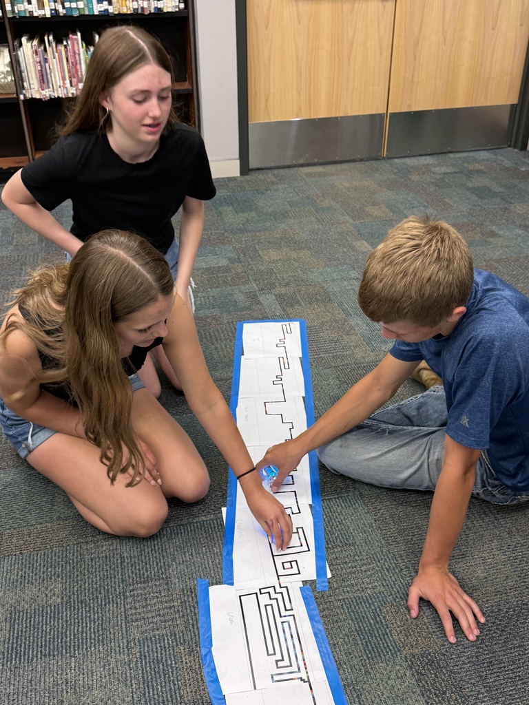 3 students with the track they made and their robot.