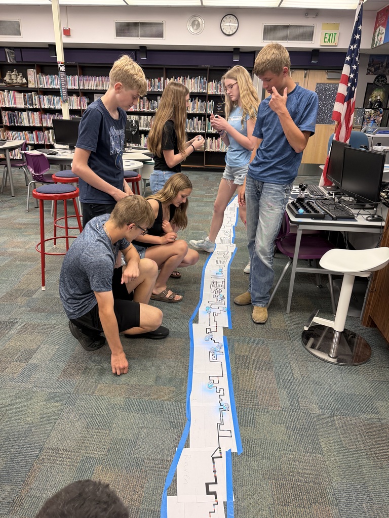 6 students ponder of the super long track they made with several robots traveling it.