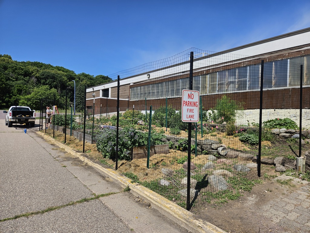 A different angle of the garden, showing the greenhouse behind it, the fence complete.