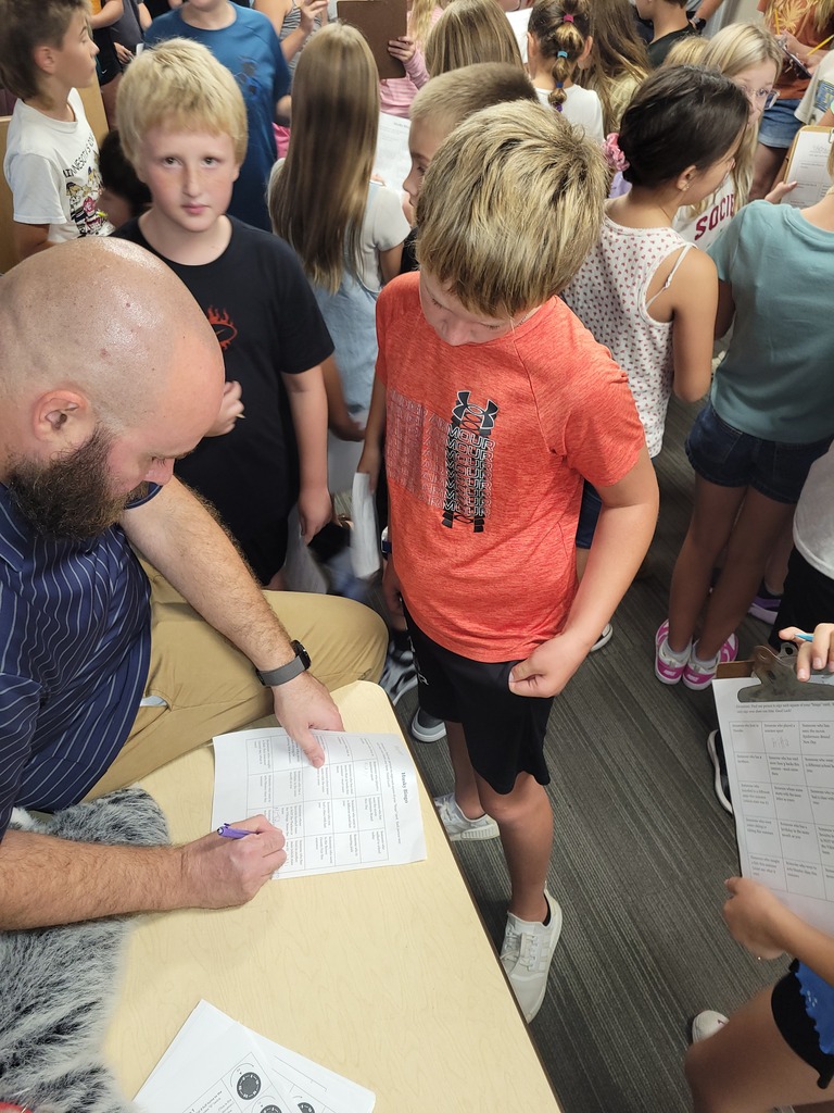 A teacher filling out part of the bingo card with a student.
