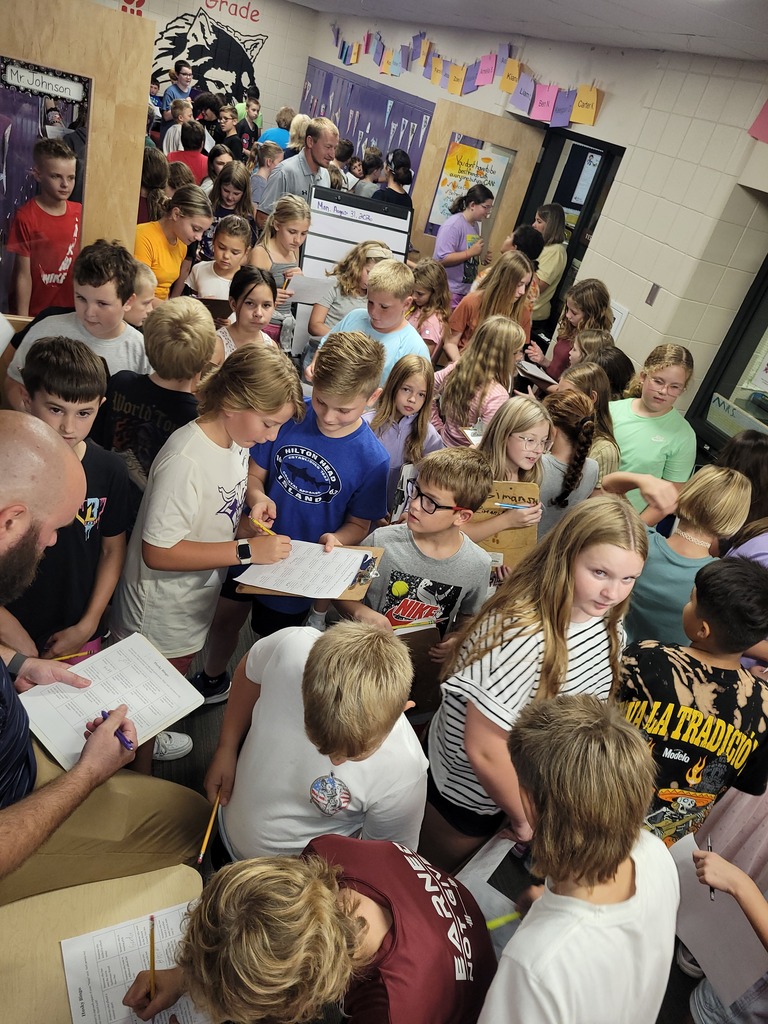 Hallway full of kids with clipboards and bingo papers talking with eachother.