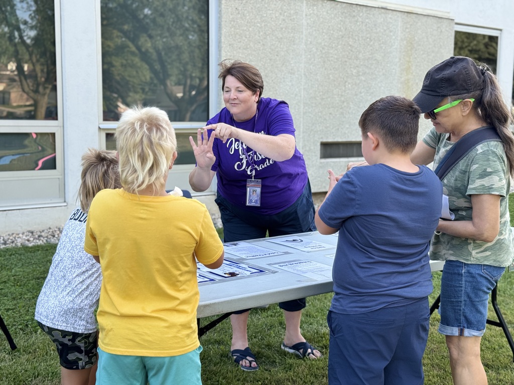 Mrs. Haroldson stands behind a table with four children, teaching them something.