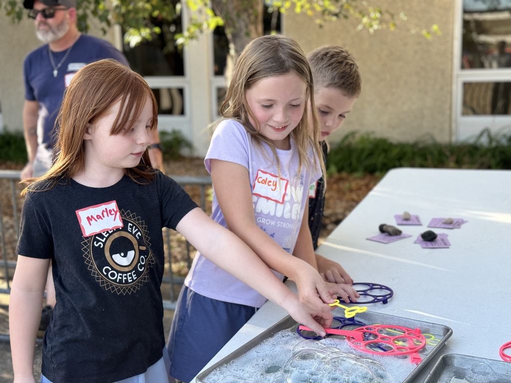 Two girls in front of a table with bubble wands.