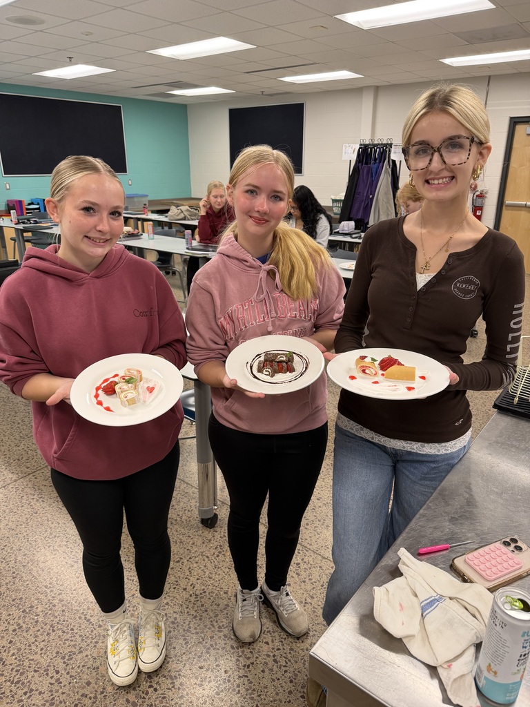 Three students pose with plates of desserts.