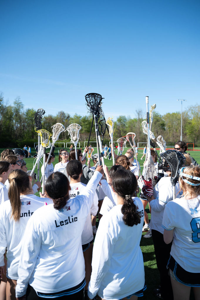varsity girls lacrosse with their sticks in the air