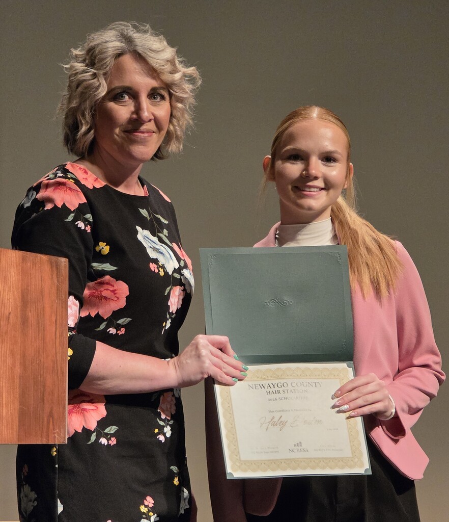 A student receives a certificate during an award presentation on stage at the event.