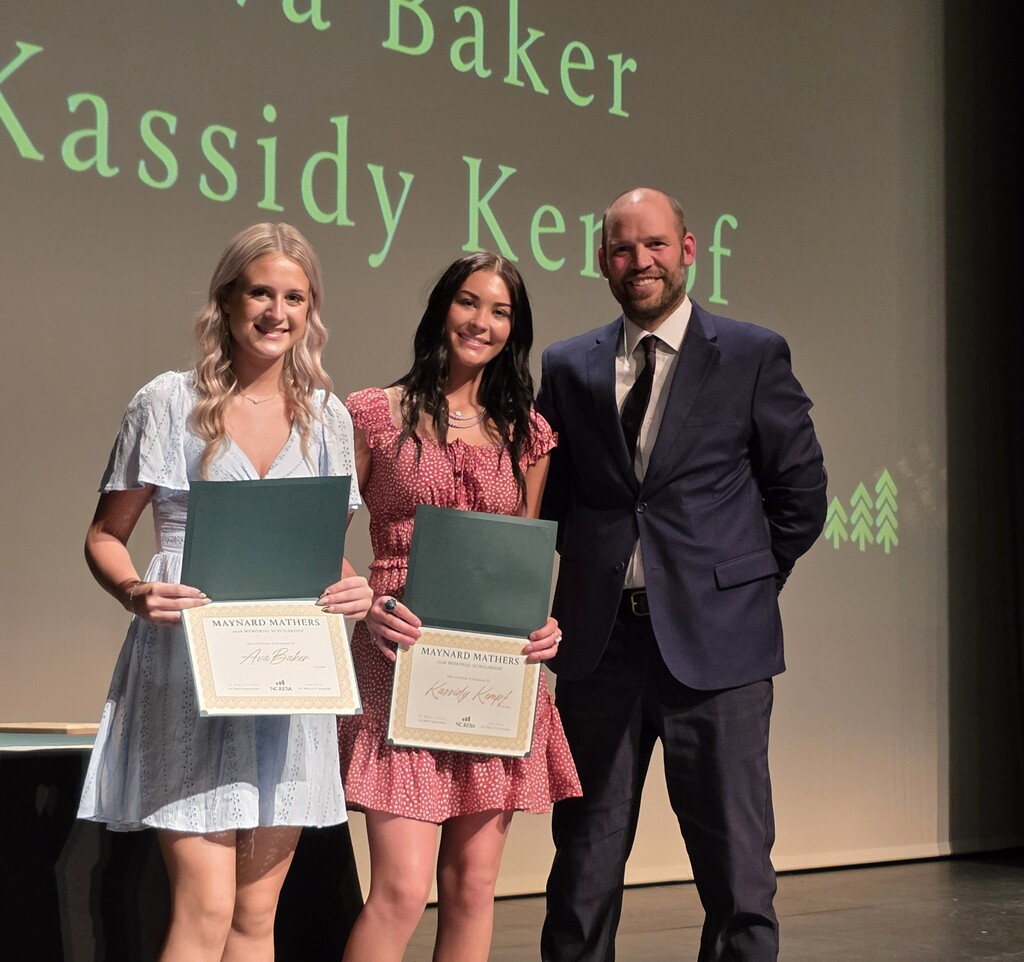 Two students hold scholarship certificates and pose for a photo in front of an NC RESA backdrop.