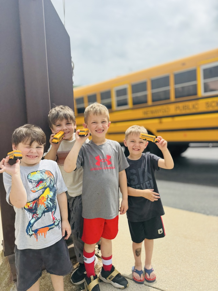 NES Field Trip students holding bus toys in front of a yellow school bus