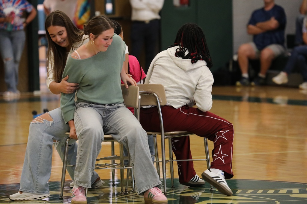 Four students playing musical chairs right as the music stops