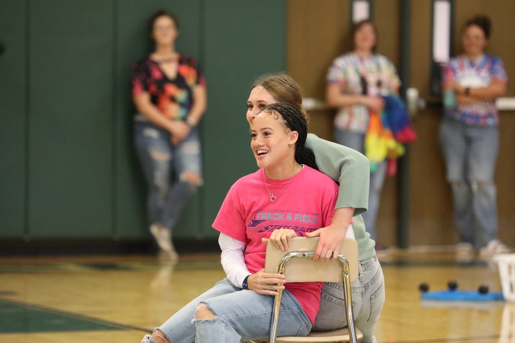 Two students trying to sit in the last chair of a game of musical chairs