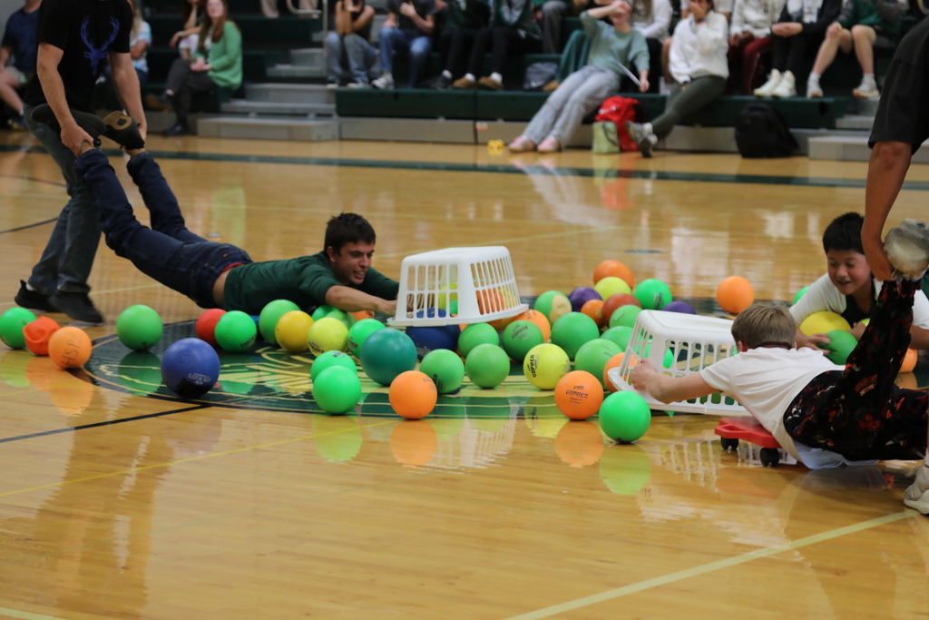 Several students on scooters being held by their legs as they play the game hungry hippos
