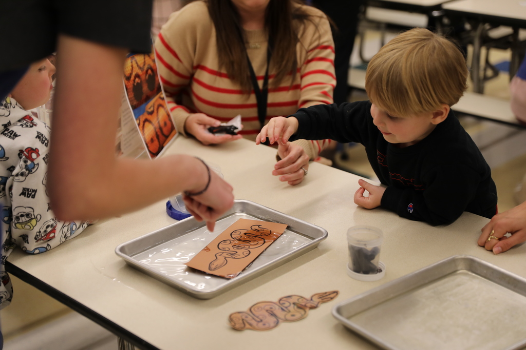 A student playing with making a snake drawing on cardboard