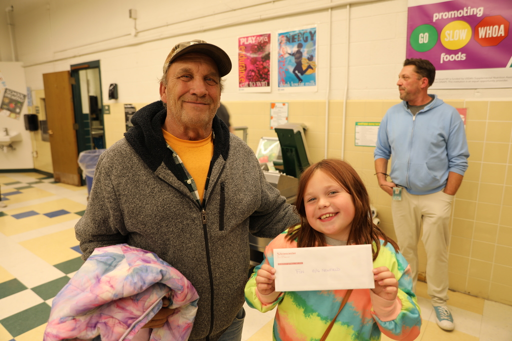 A student and parent posing for camera as they hold up a raffle prize