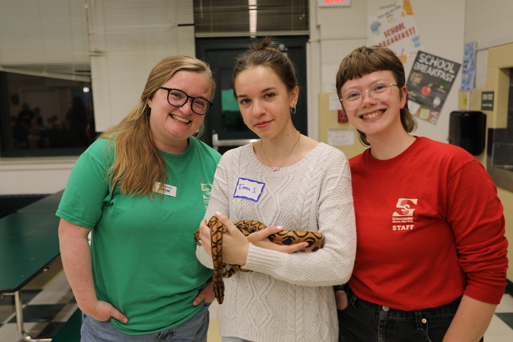 Three staff members holding a snake