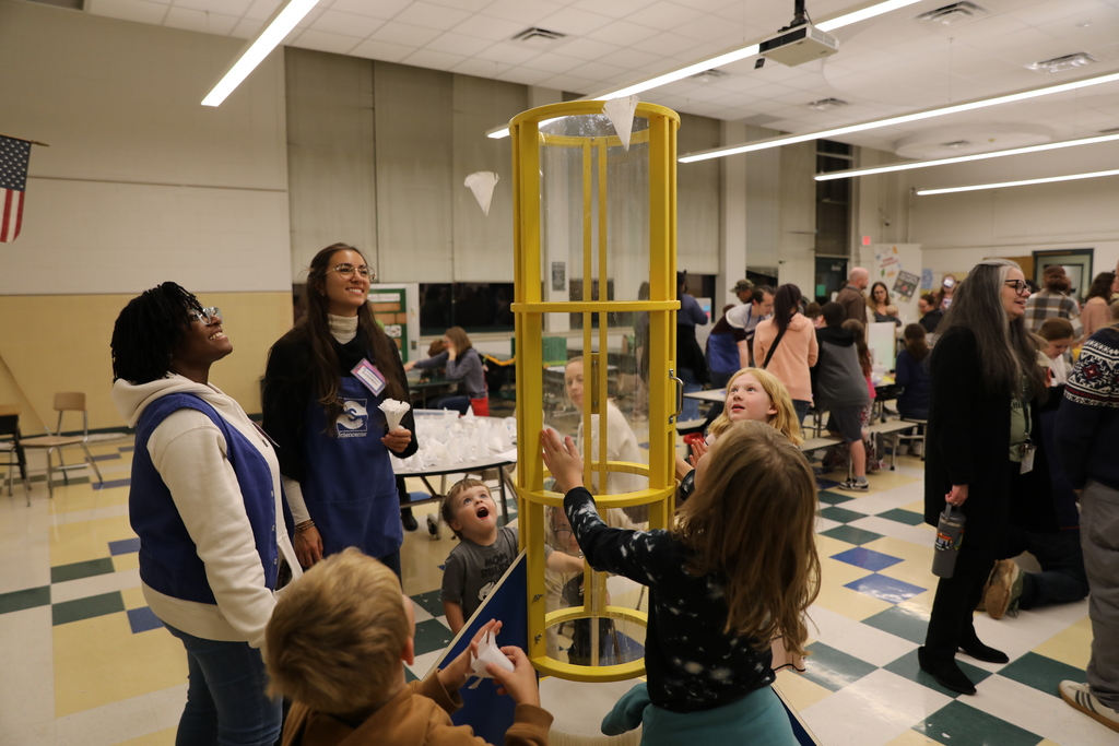 Students playing with the paper cups that get floated away by a fan machine