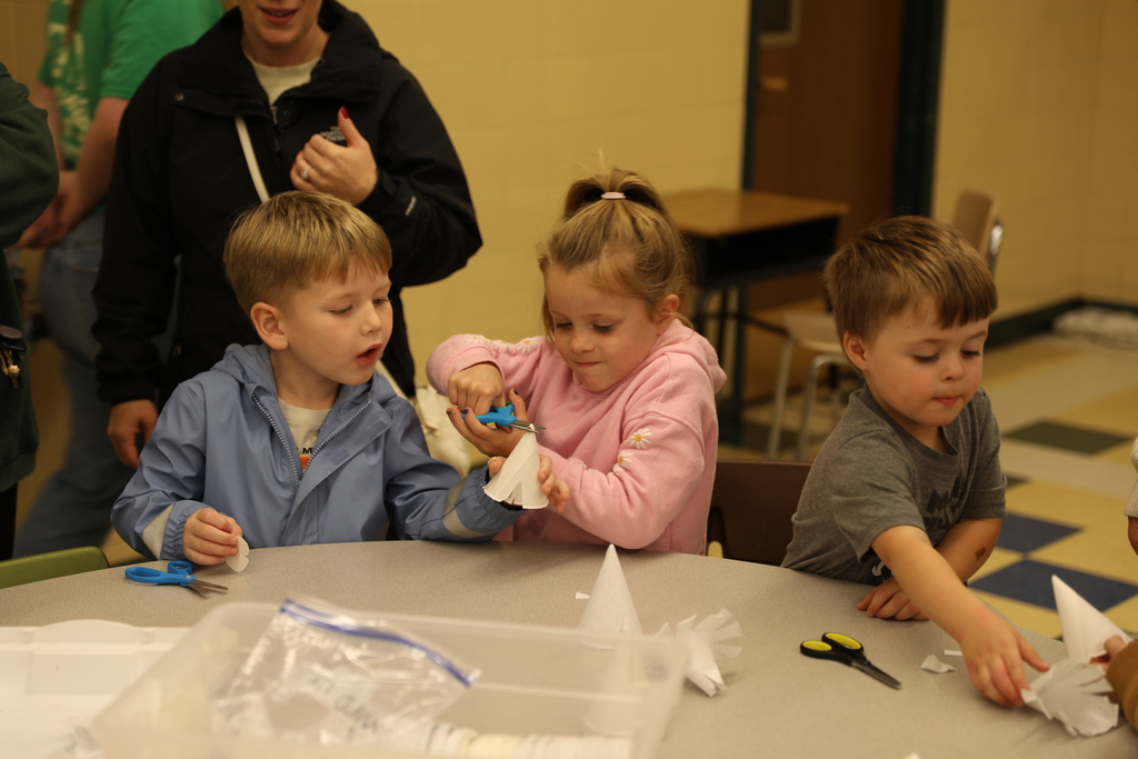 three students cutting out paper cups 