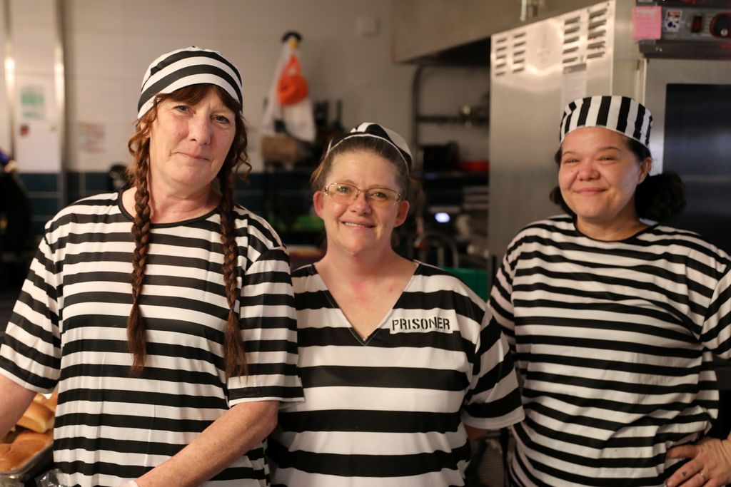 Three adults dressed as prisoners in the lunch room