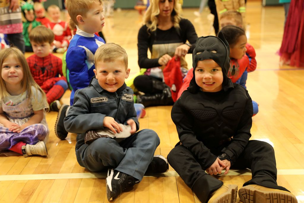Some students smiling at camera, one dressed as batman