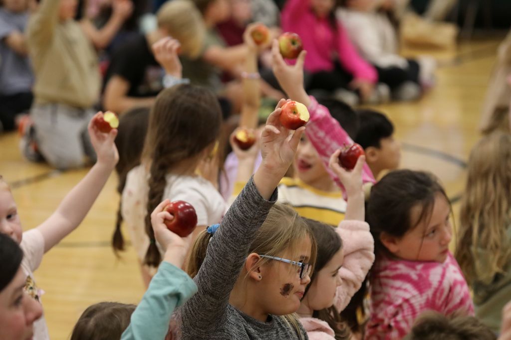 Students holding up apples