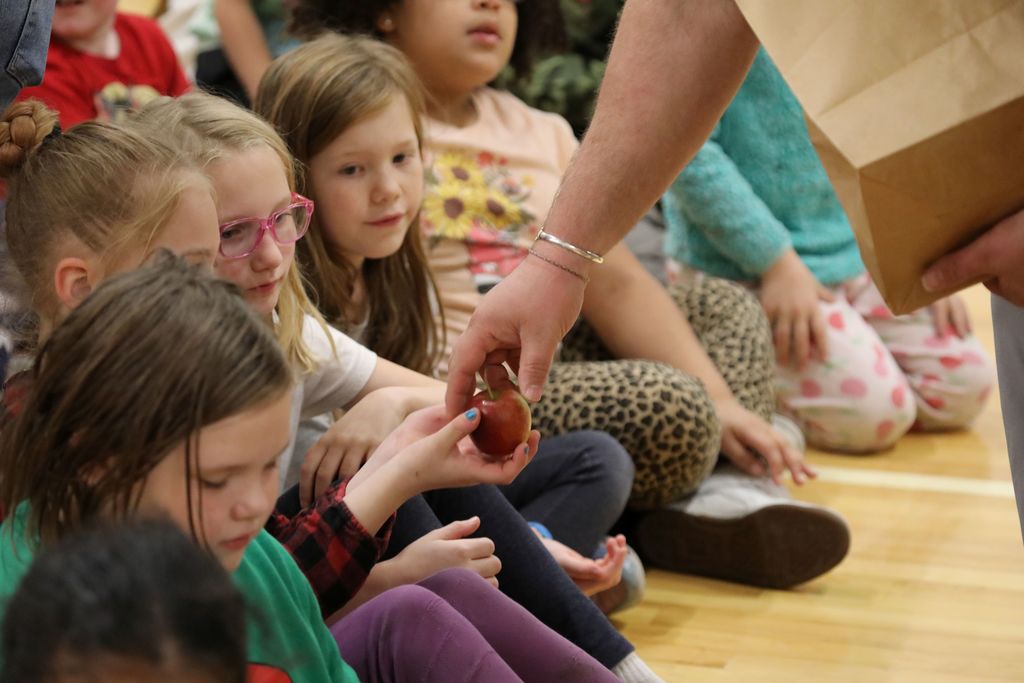 student being handed an apple