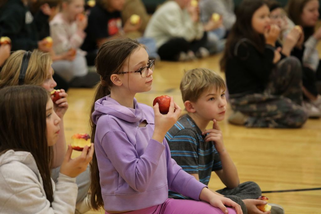 students holding the apples and listening 