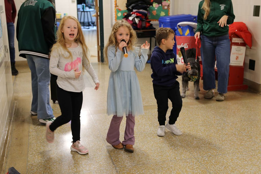 Two students singing as another dances