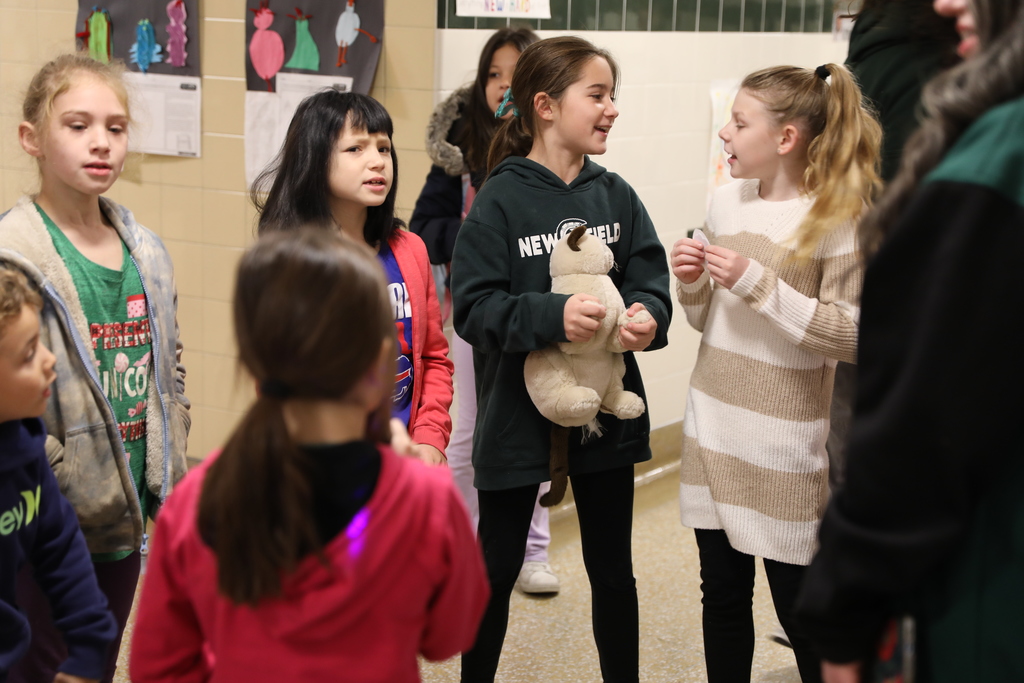Four students standing in the morning smiling, one holding a stuffed animal