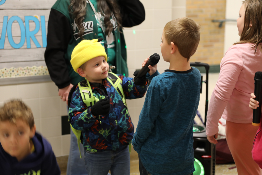 A student holding the mic up to another student to sing