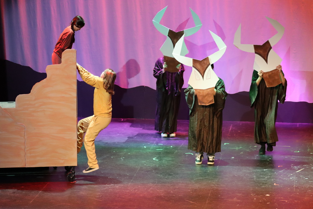 5 students acting out a scene, three are holding up buffalo masks