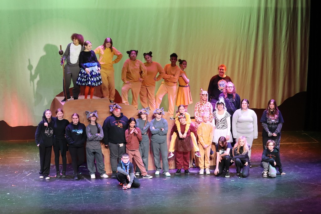 A cast photo with the whole cast standing on stage