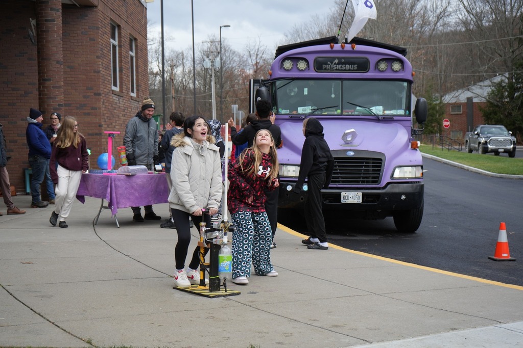 two students looking at sky after launching bottle into air