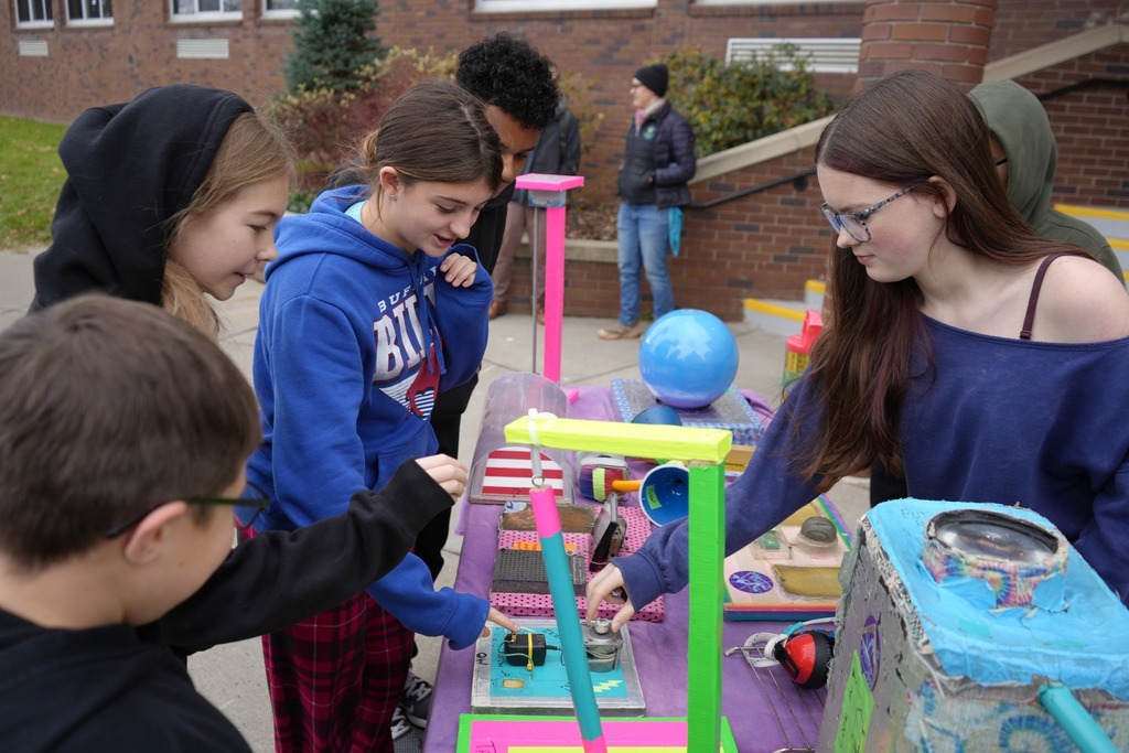 group of students interacting with items on physics bus table