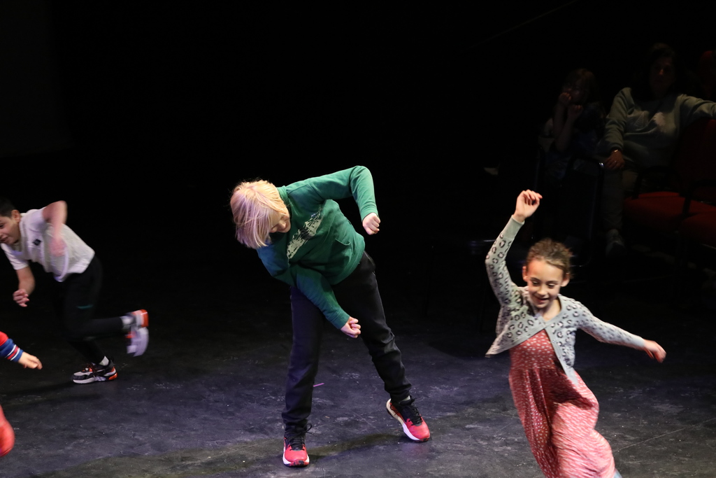 Three students moving wildly as they enact part of their play