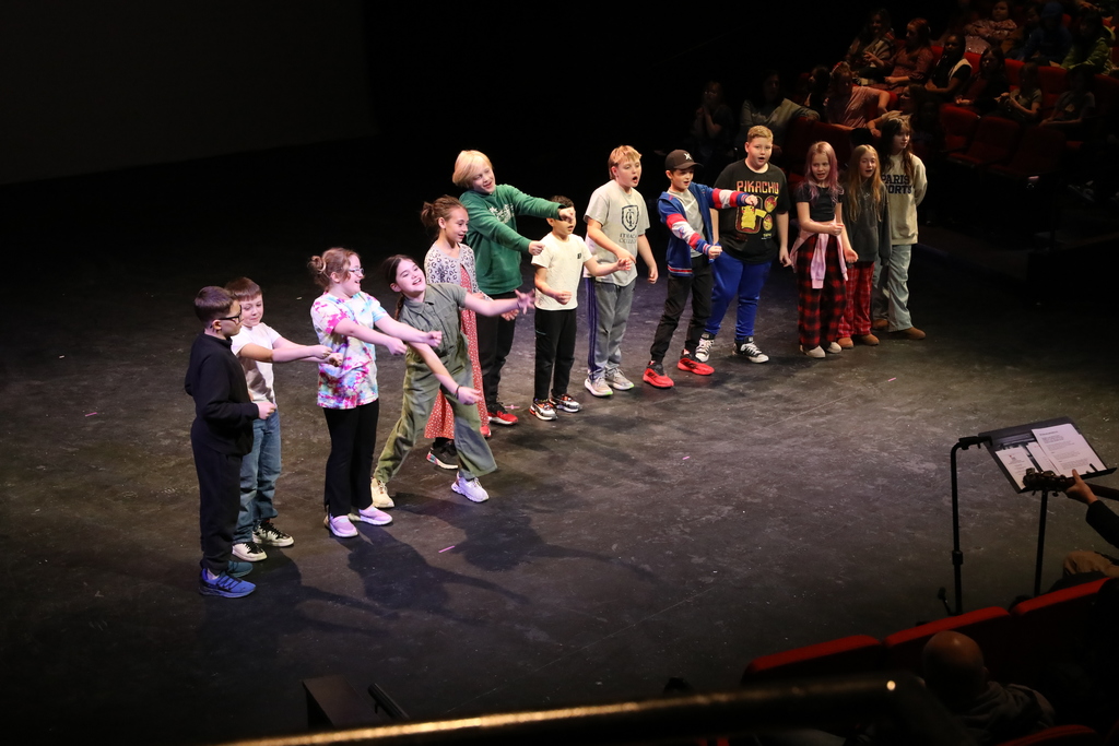 a group of students on stage performing a song
