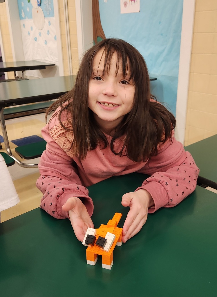 Student smiles while holding up an orange LEGO animal they built during LEGO Enrichment in the After School Program.