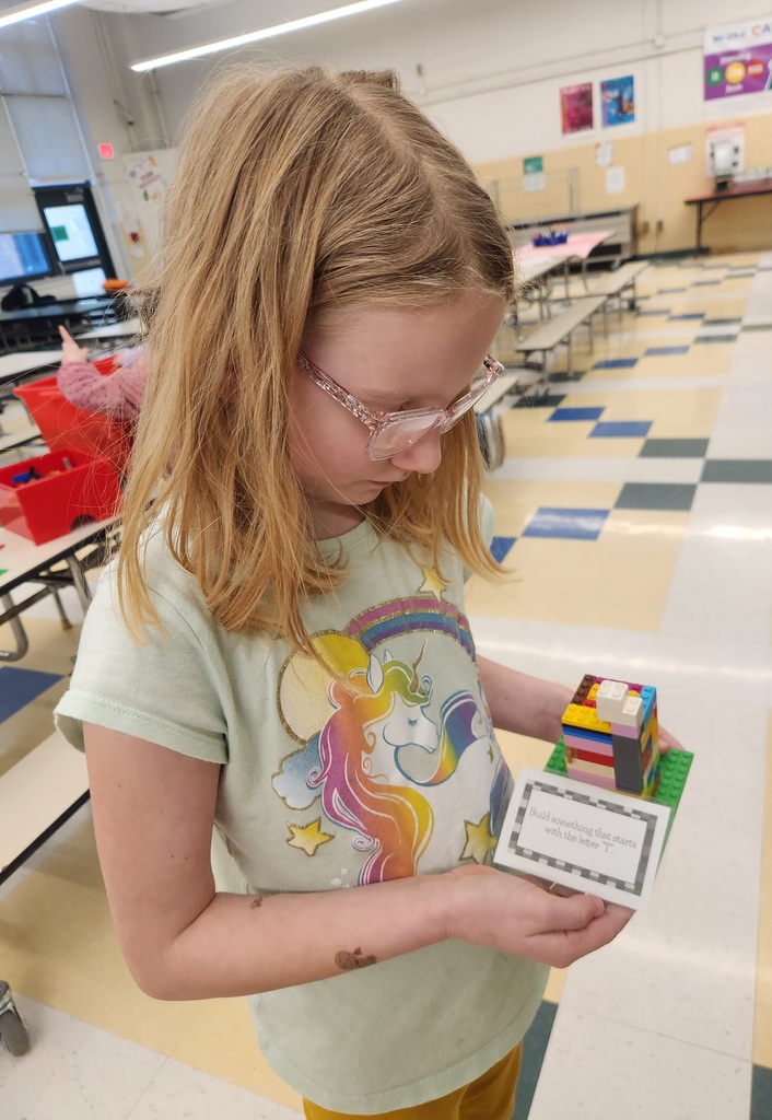 Student stands holding a small LEGO structure they built during the Green Group LEGO Enrichment session.
